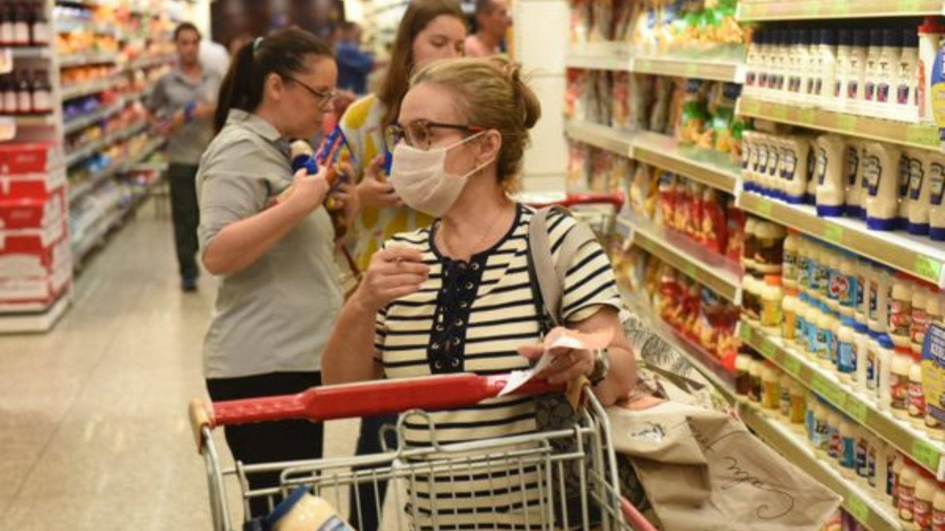 Foto de uma mulher dentro de um supermercado fazendo compras.