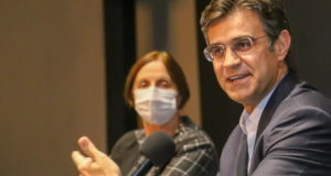Rodrigo Garcia tenta se afastar de Doria e busca eleitores de 'esquerda e direita'. Ele aparece em foto sorrindo, utiliza um terno cinza, óculos de grau e cabelo grisalho.