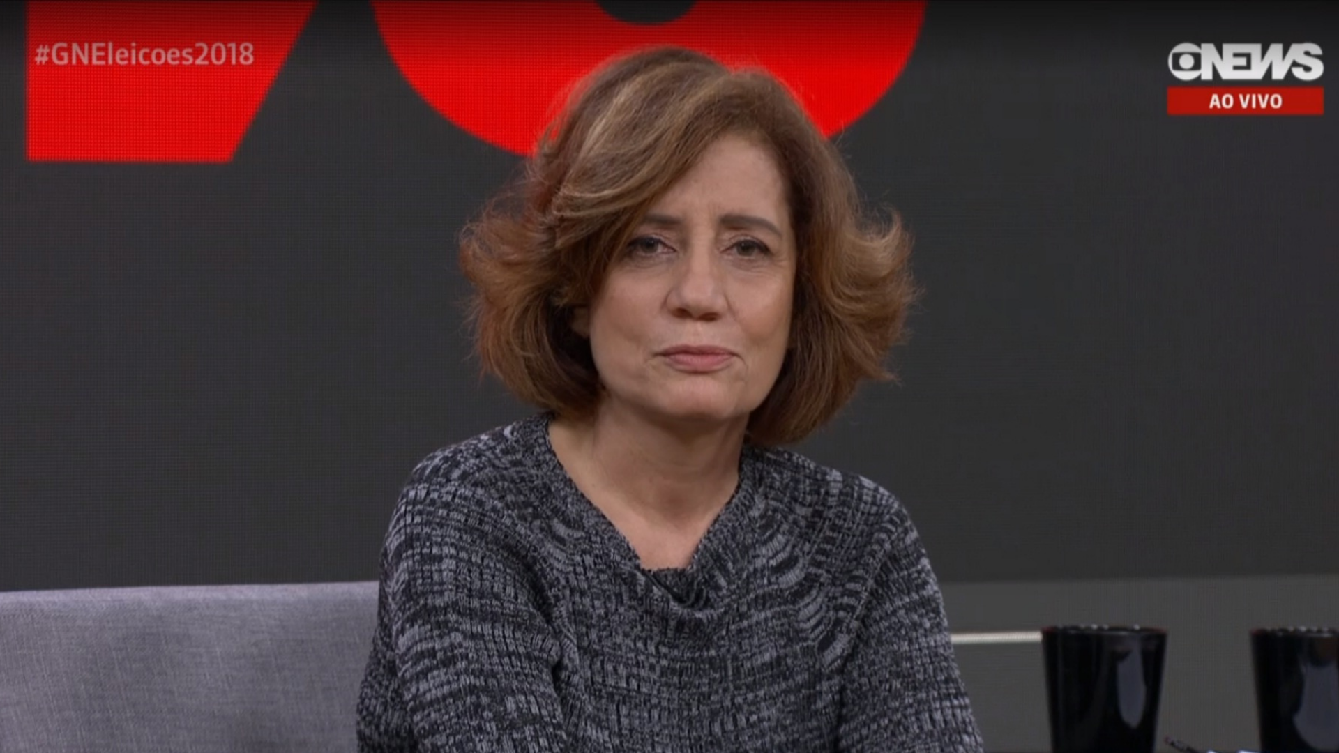 Leia o depoimento de Míriam Leitão sobre a tortura alvo de deboche de Eduardo Bolsonaro. Ela aparece utilizando um vestido cinza enquanto fala em um programa da GloboNews,