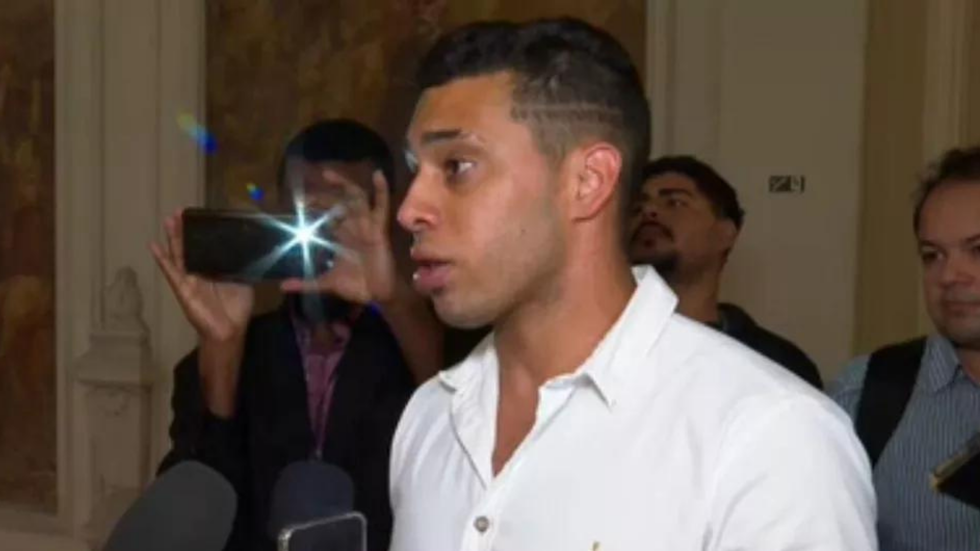Gabriel Monteiro pode ser expulso do PL. Foto de gabriel Monteiro com olhar desconcertado enquanto dá entrevista à uma emissora. Ele usa uma camisa branca.