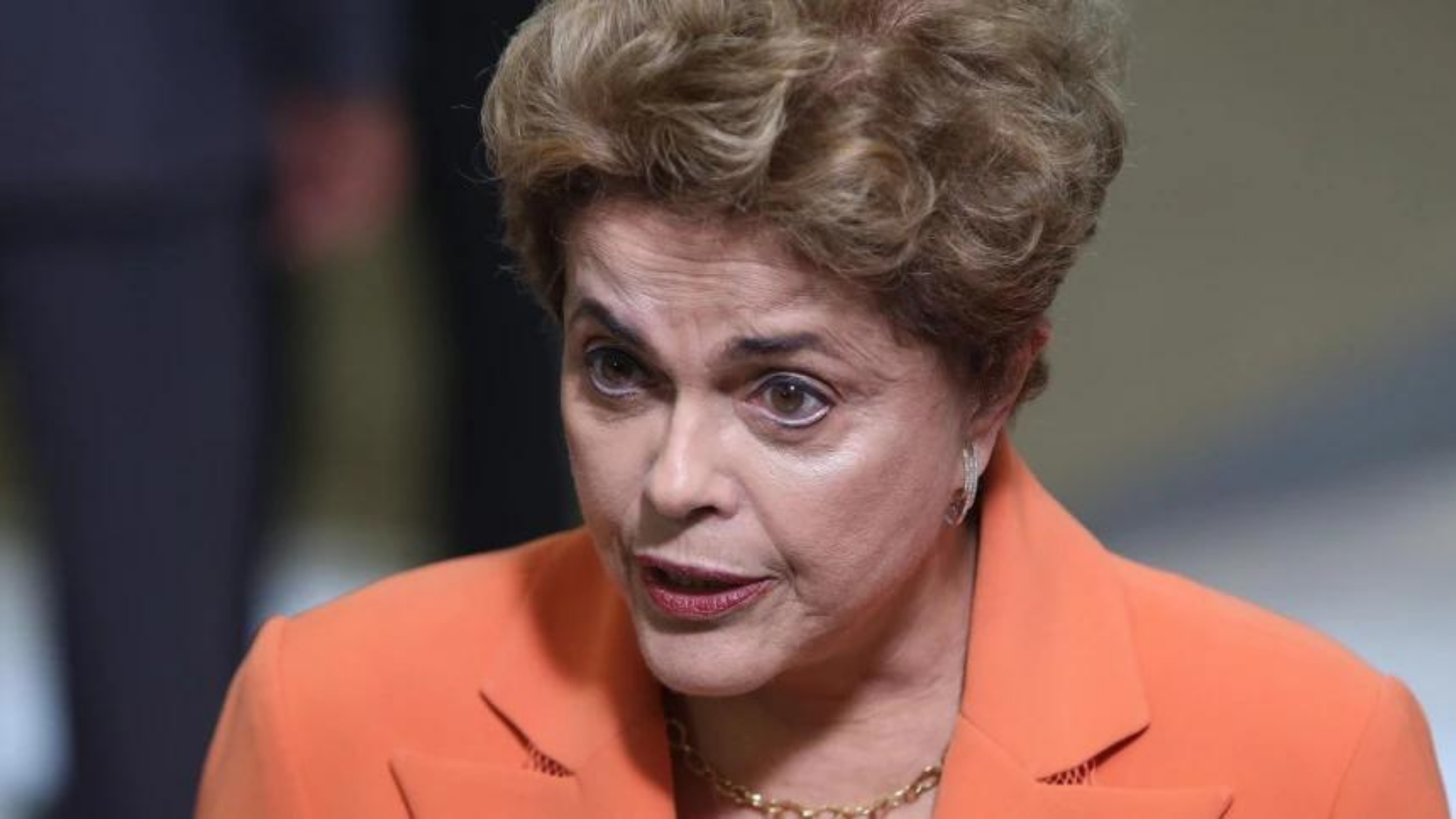 Dilma tem expressão séria e olha para a câmera. 