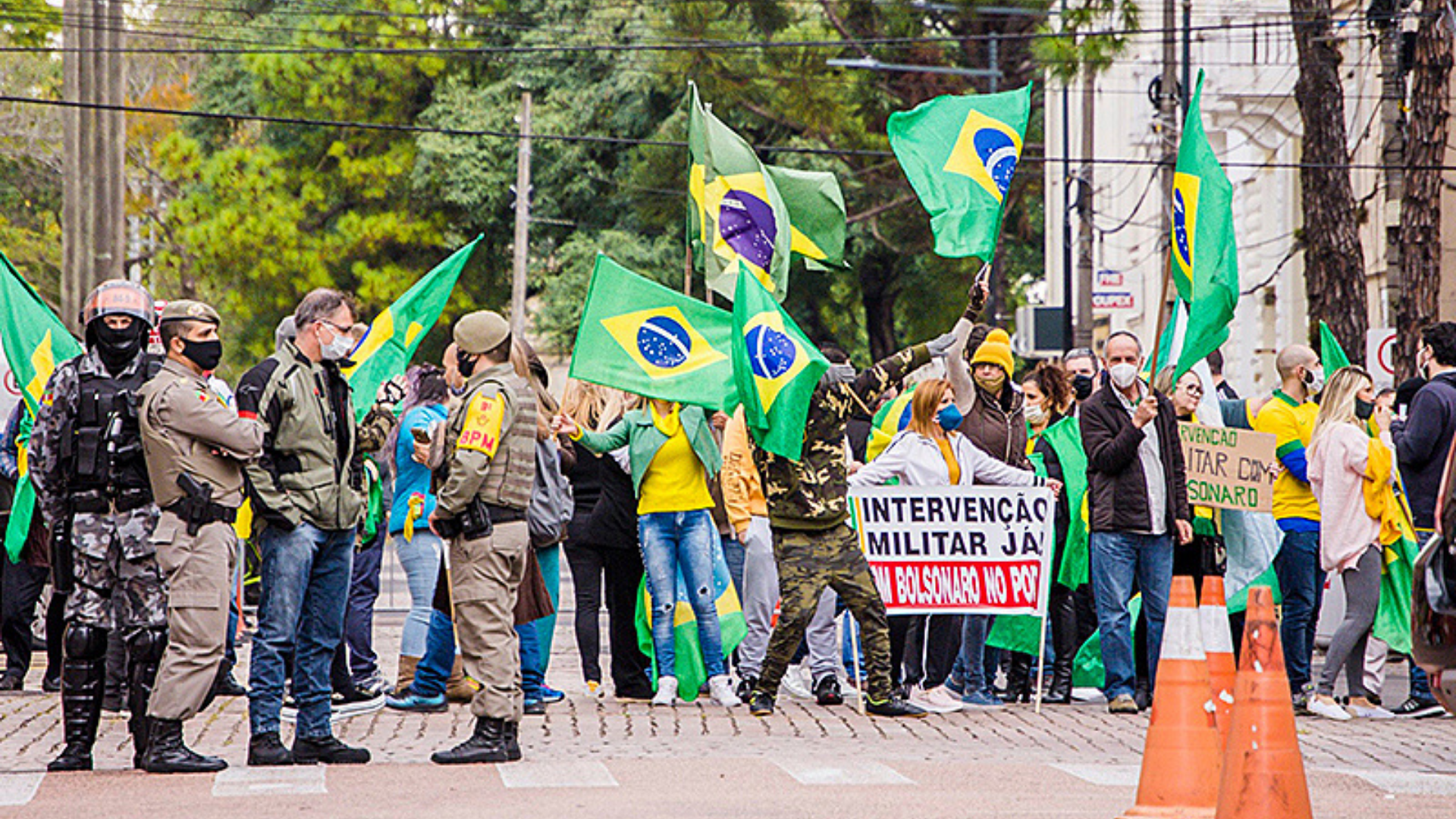 Foto de manifestantes bolsonaristas com camisas do Brasil, bandeiras do país e cartazes com frases conservadoras. 