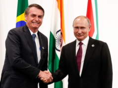 Foto de Bolsonaro sorrindo com aperto de mão em Vladimir Putin, presidente russo.