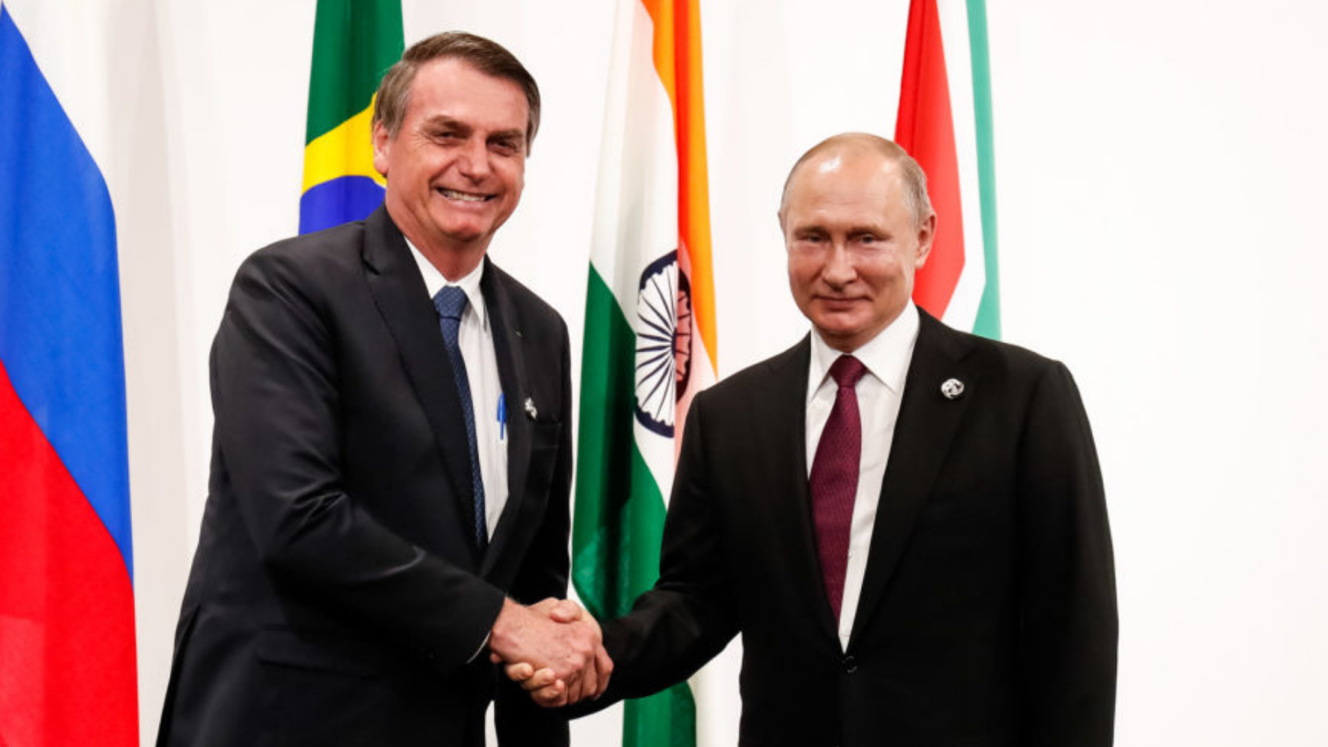 Foto de Bolsonaro sorrindo com aperto de mão em Vladimir Putin, presidente da Rússia. 