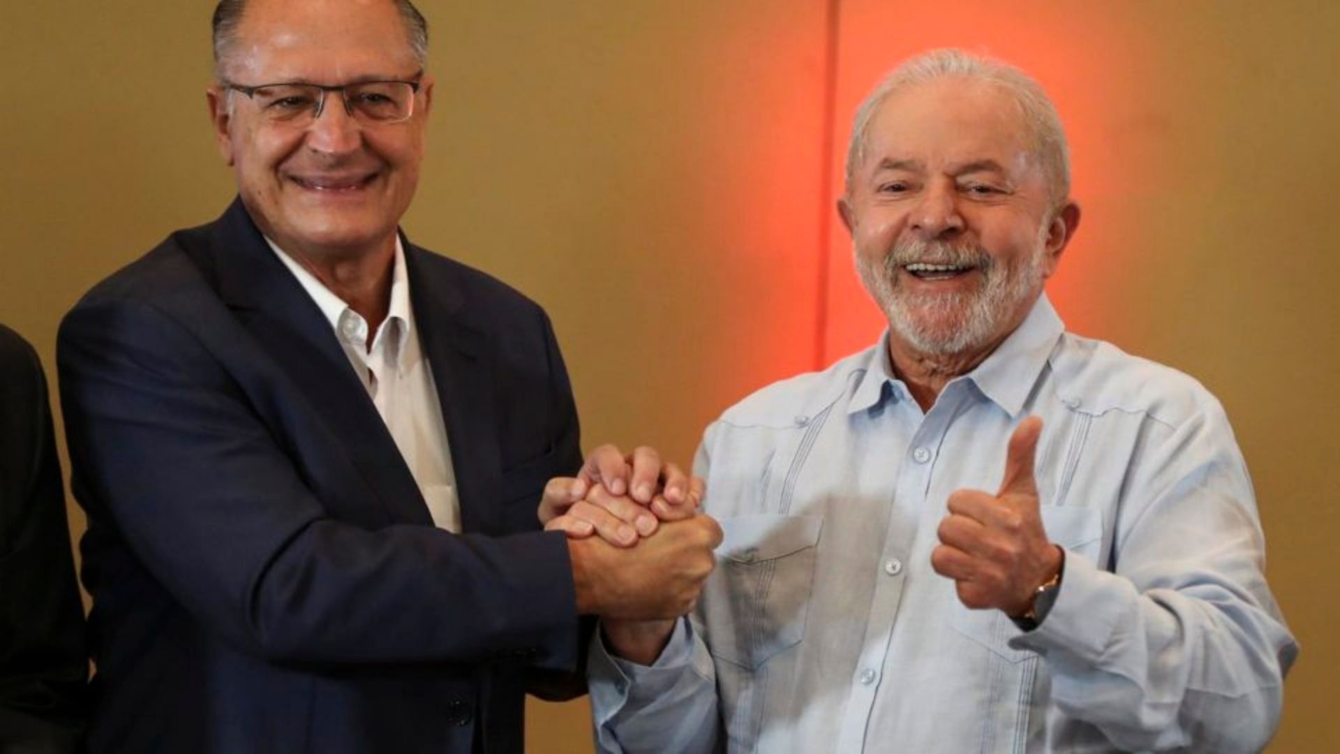 Foto de Lula sorrindo ao lado de Geraldo alckmin. Os dois estão dando um aperto de mãos.