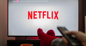 Imagem de uma pessoa deitada com a TV na Netflix.
