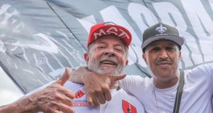 Lula, com boné do MST, posando para foto com Mano Brown.