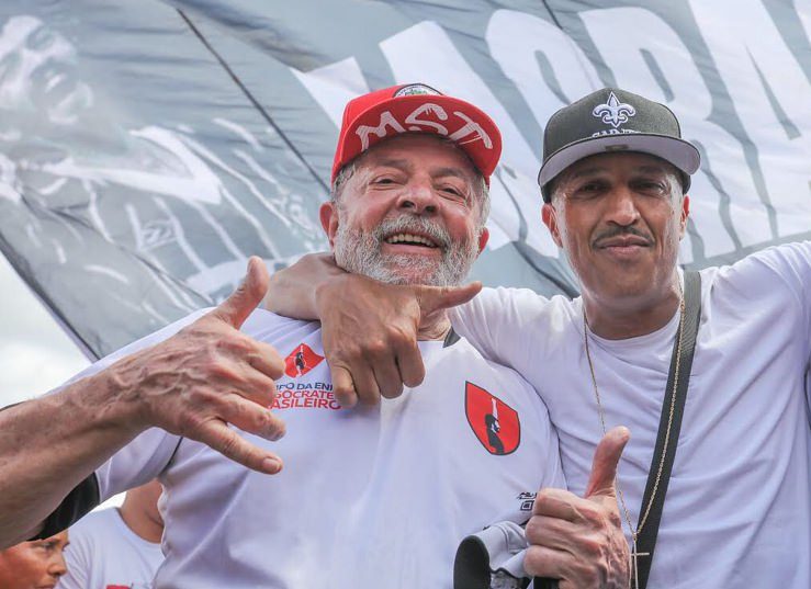 Lula, com boné do MST, posando para foto com Mano Brown.