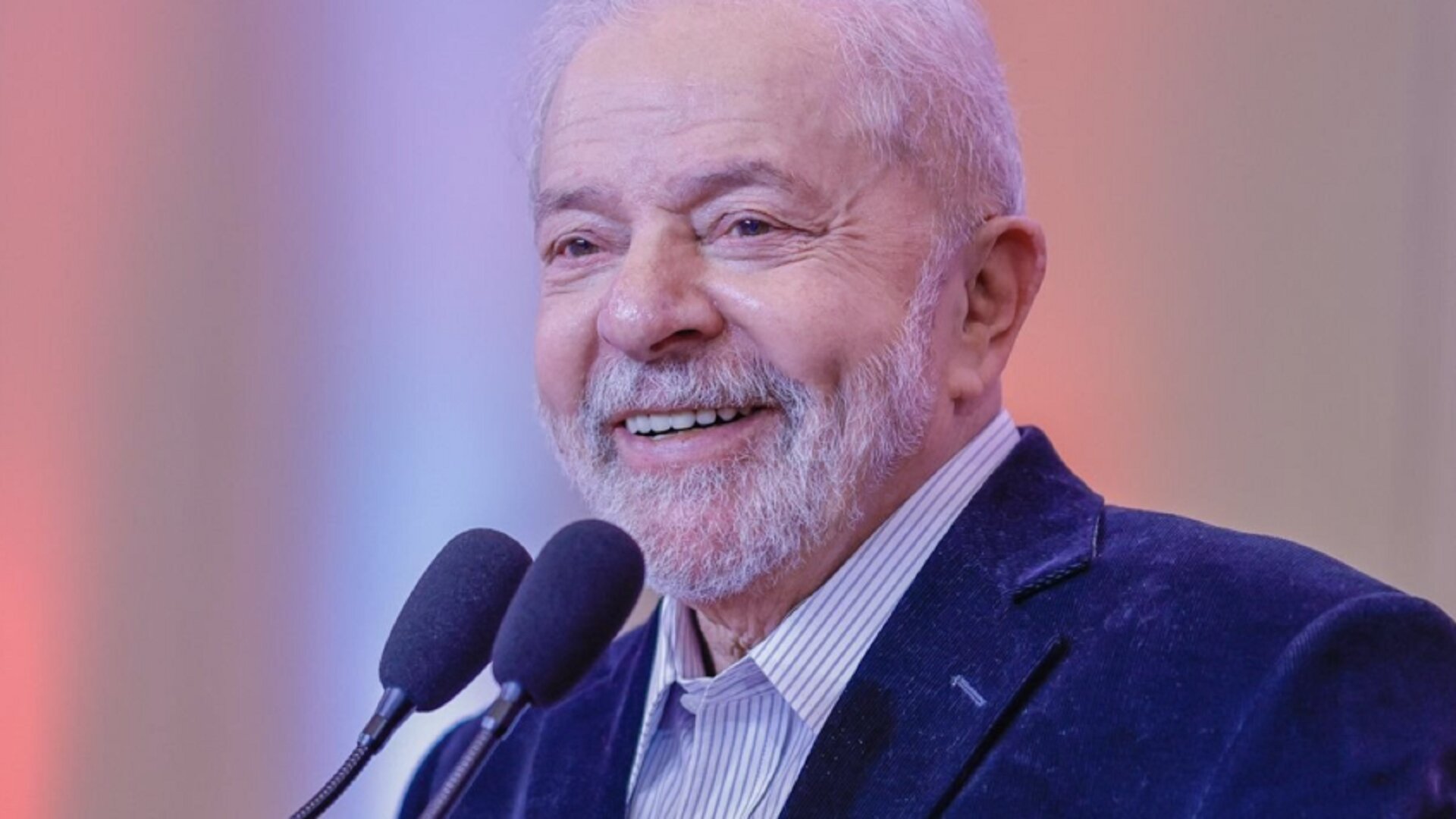 Lula sorrindo ao falar no microfone.