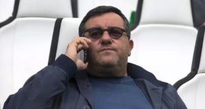 O agente Mino Raiola sentado, usando óculos escuros e falando ao celular.
