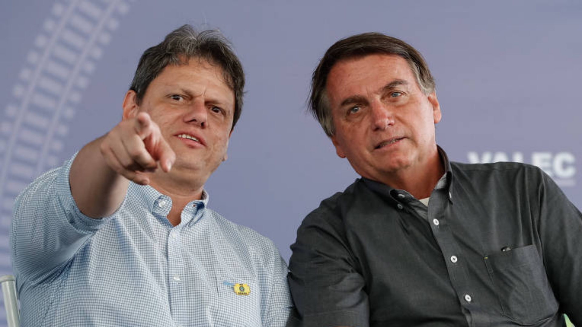 Tarcísio Freitas ao lado de Jair Bolsonaro. Tarcísio aponta para algum lugar e Bolsonaro se inclina para ver.