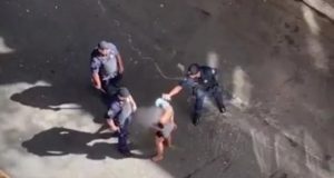 foto de alto mostrando dois guardas civis agredindo uma mulher na rua.