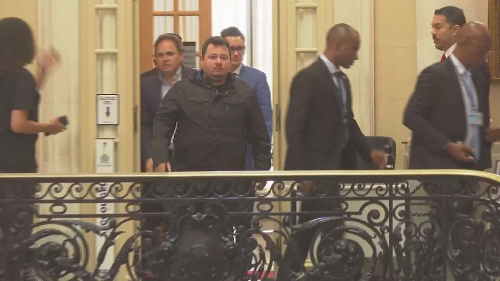 Foto de Vinícius Hyden em depoimento. Eeles está em pé, com roupas prestas e olhar sério.