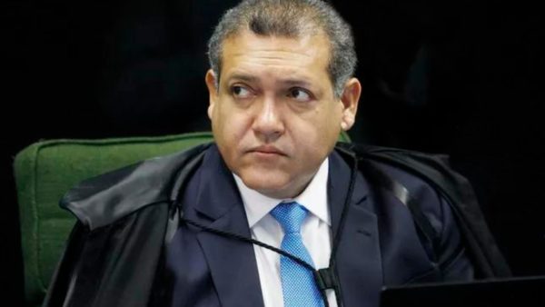 Foto de Nunes Marques com olhar sério falando no plenário do STf no telefone.