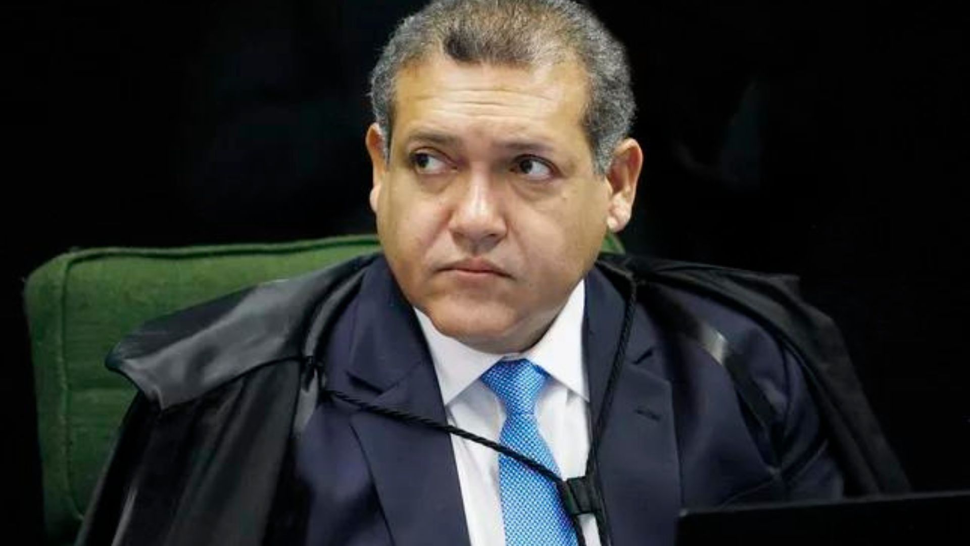 Foto de Nunes Marques com olhar sério falando no plenário do STf no telefone.