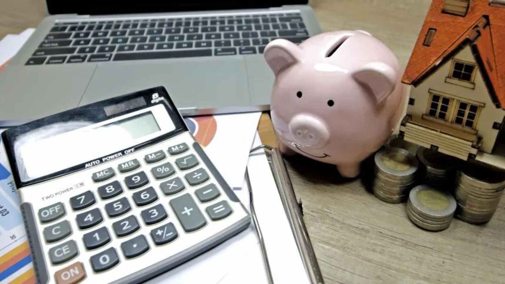 foto de um cofre em fortamo de porquinho com uma calculadora e notebbok.