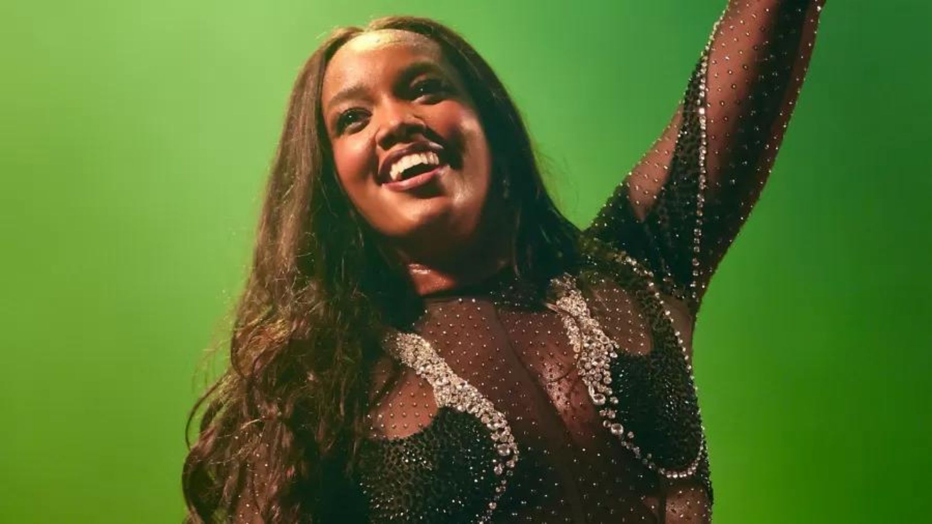 Foto de Iza sorrindo para o público. Ela tem pele negra, cabelos pretos e sorriso no rosto.