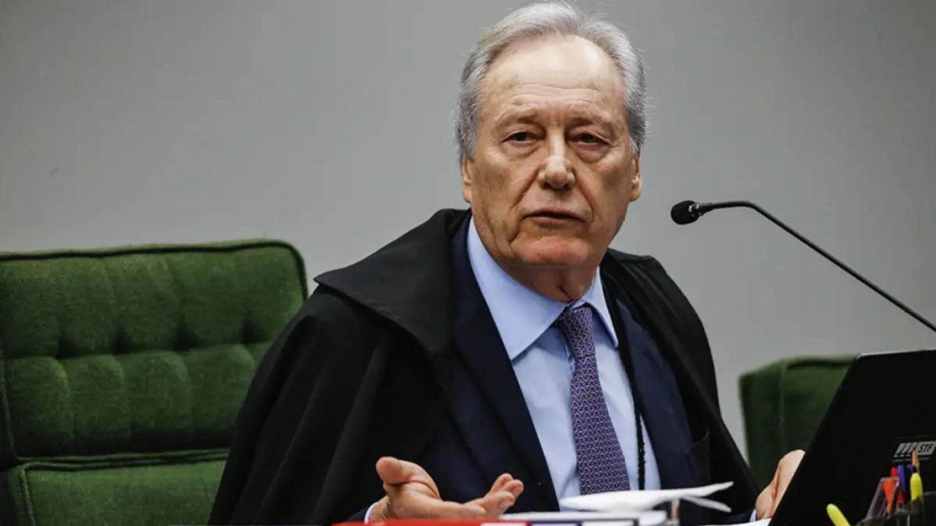 Foto do ministro Ricardo Lewandowski com uma batina na cor preta, gravata rocha, pele e cabelos brancos. Ele faz um sinal de desdém.