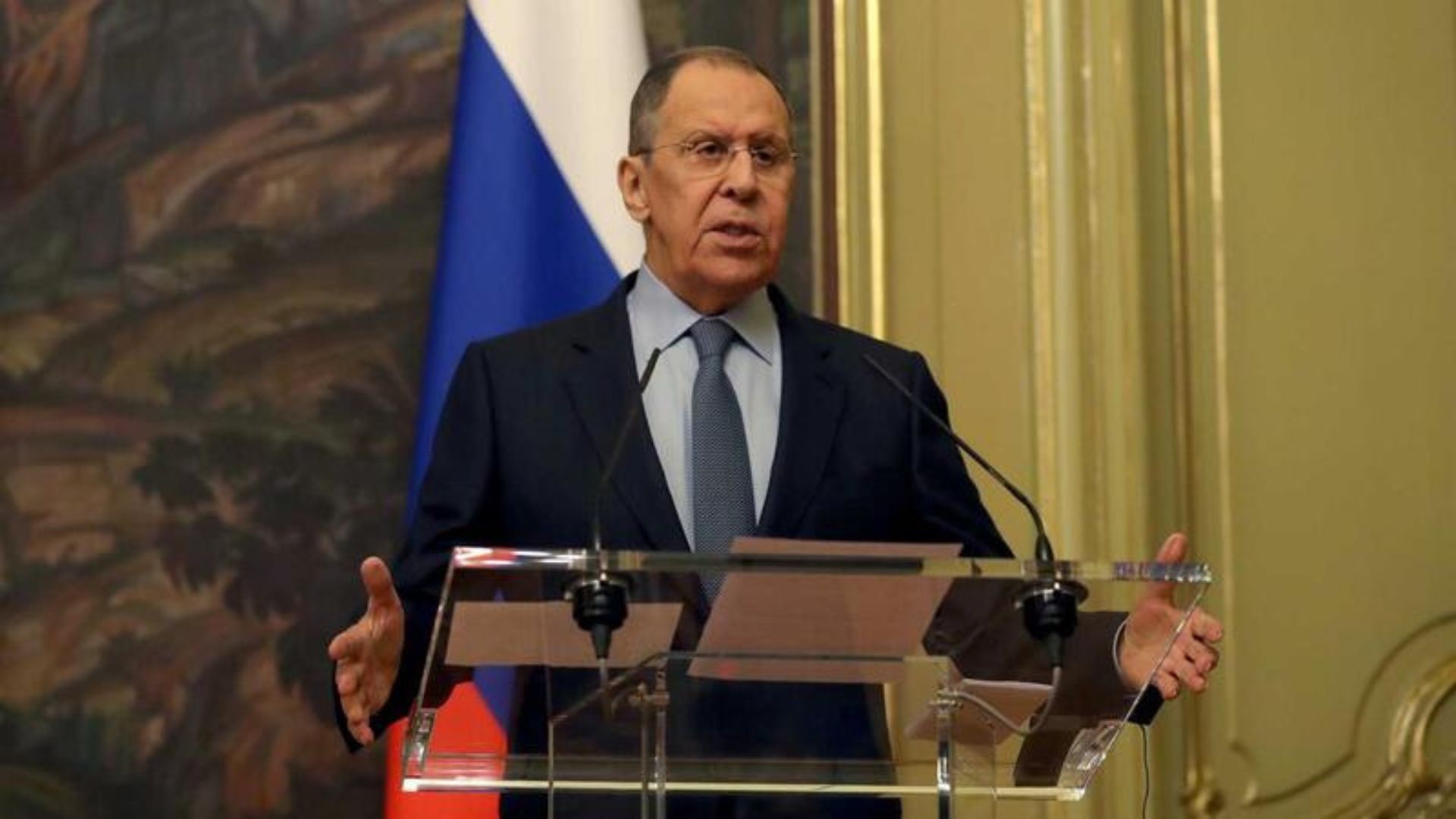 Sarguei Lavrov falando em um oúkpito. Ele veste terno preto e usa óculos.