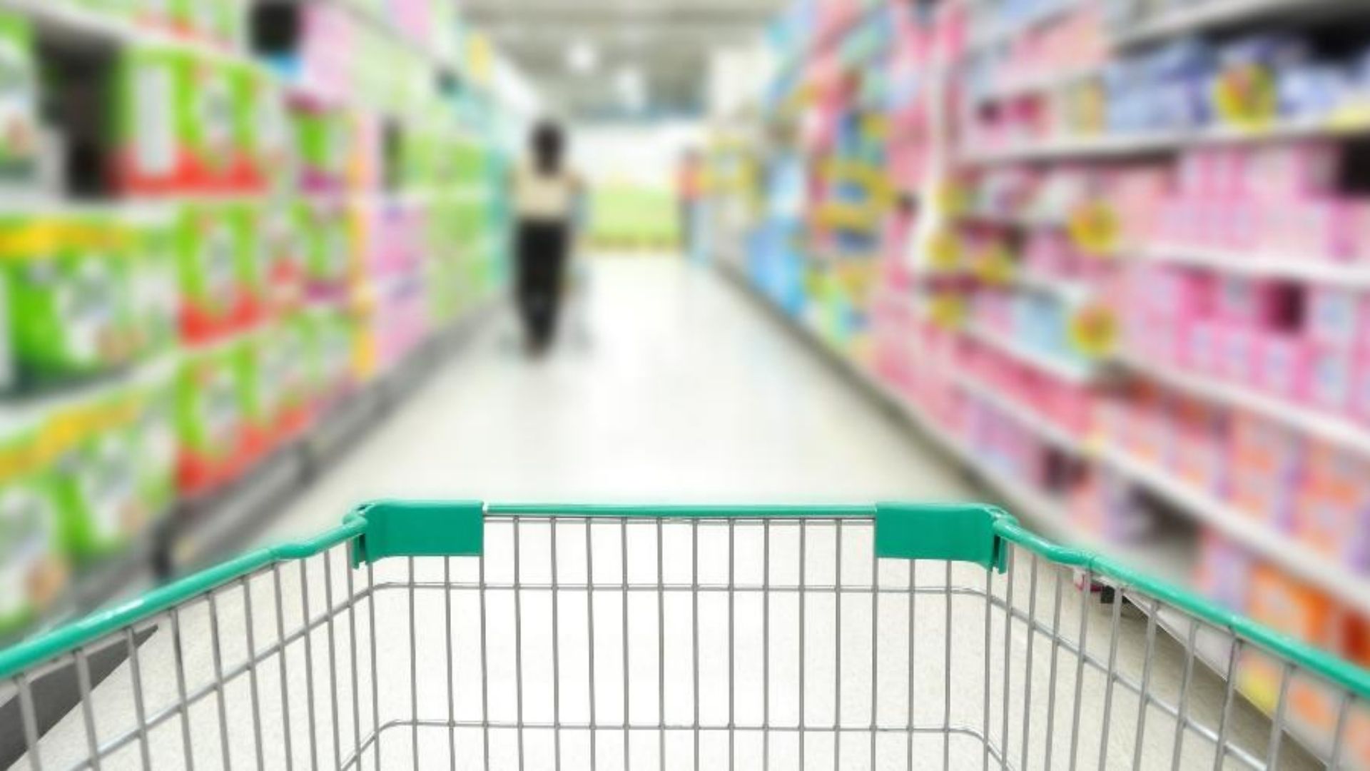 Foto de carrinho de supermercado na cor ver com um corredor ao fundo desfocado.