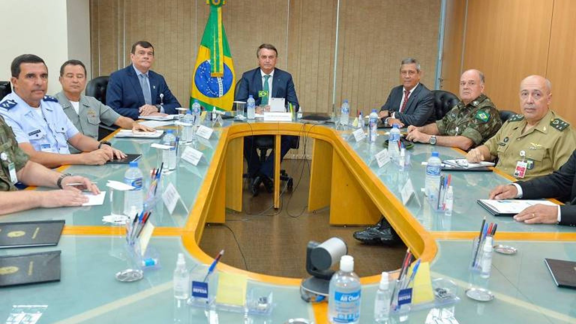 foto de bolsonaro e representantes militares em uma mesa de reuniões no formato oval.