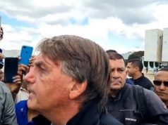 Foto de Bolsonaro falando a apoiadores, ele usa roupa preta, tem cabelo grisalho, pele branca e expressão de intimidação.