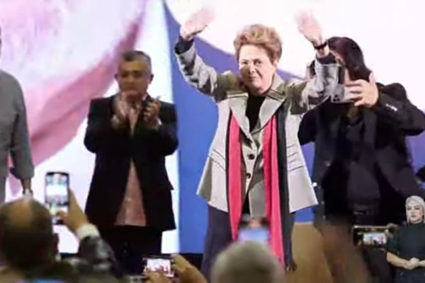 Dilma no palco cumprimentando a saudação do público.