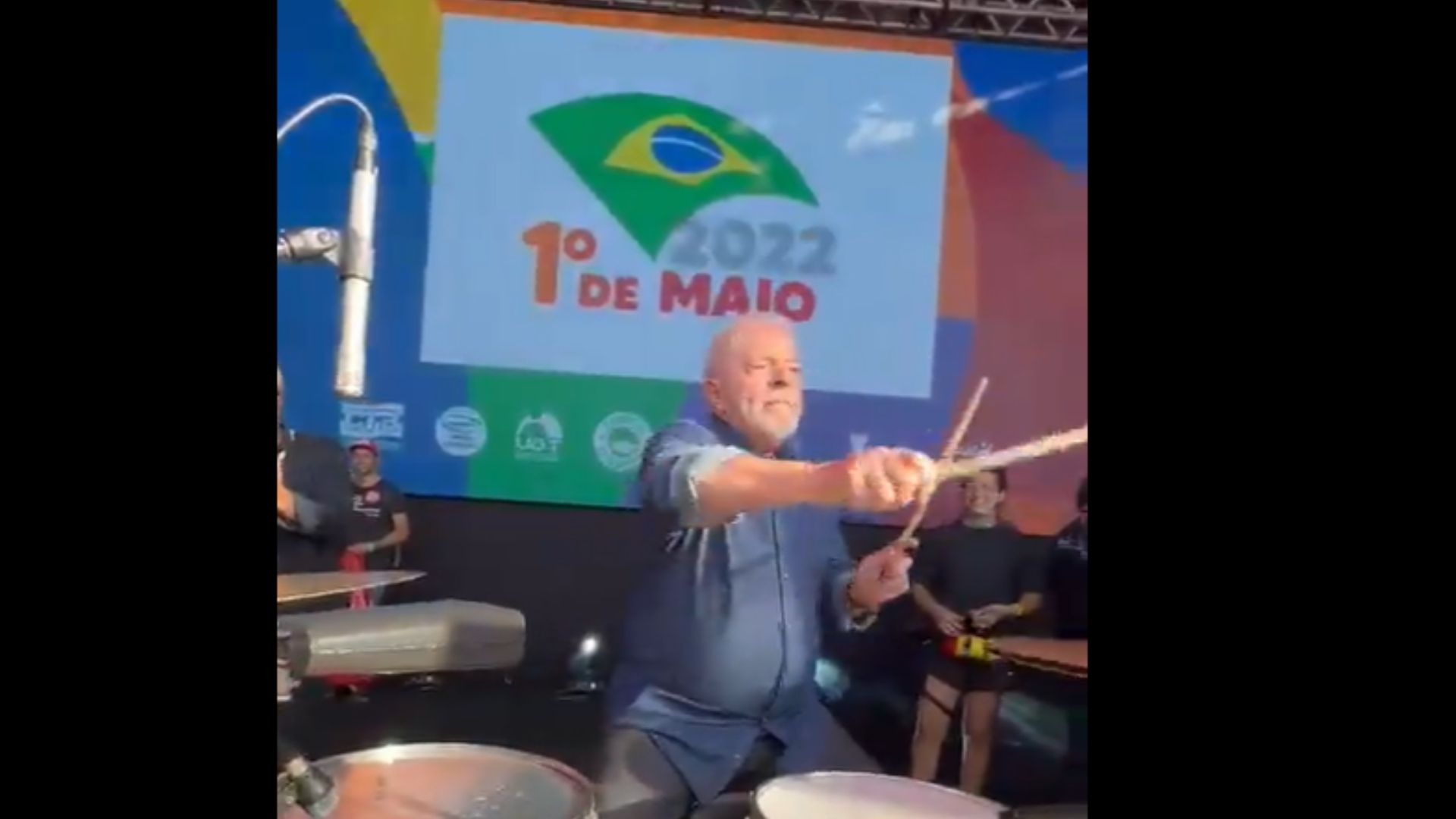 Lula está sentando em uma cadeira enquanto toca a bateria no Pacaembu.
