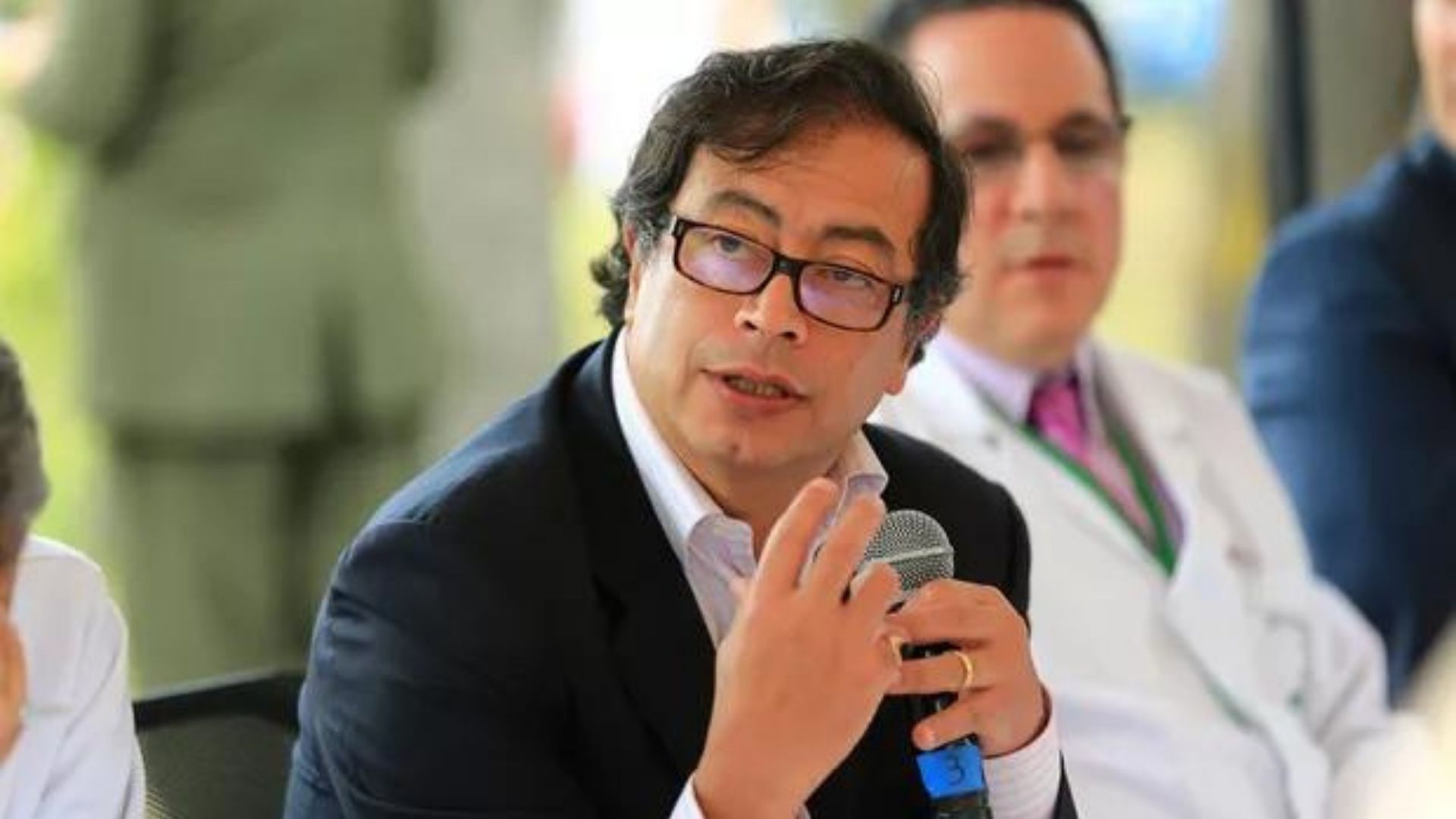 Foto de Gustavo Petro com óculos de grau, terno preto, pele branca.