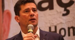 Foto de Moro flando ao microfone com olhar assustado.