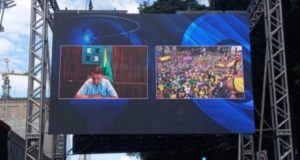 Foto de um telão na Avenida Paulista mostrando o presidente Bolsonaro em uma videochamada.