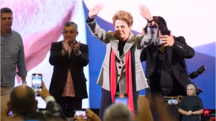 Dilma no palco cumprimentando a saudação do público.