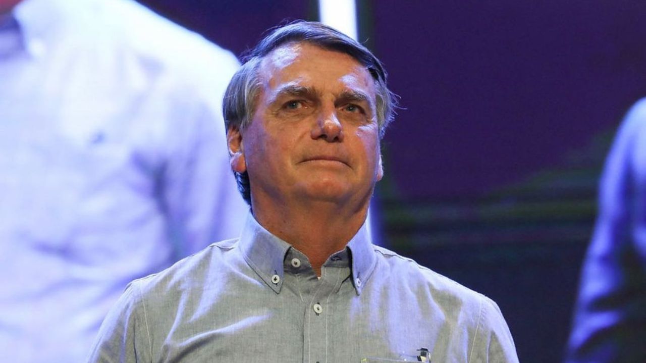 Jair Bolsonaro de camisa social azul clara, olhando pra frente sem sorrir