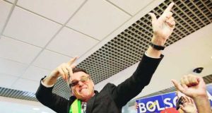 Bolsonaro fazendo gesto de armas com os braços e as mãos