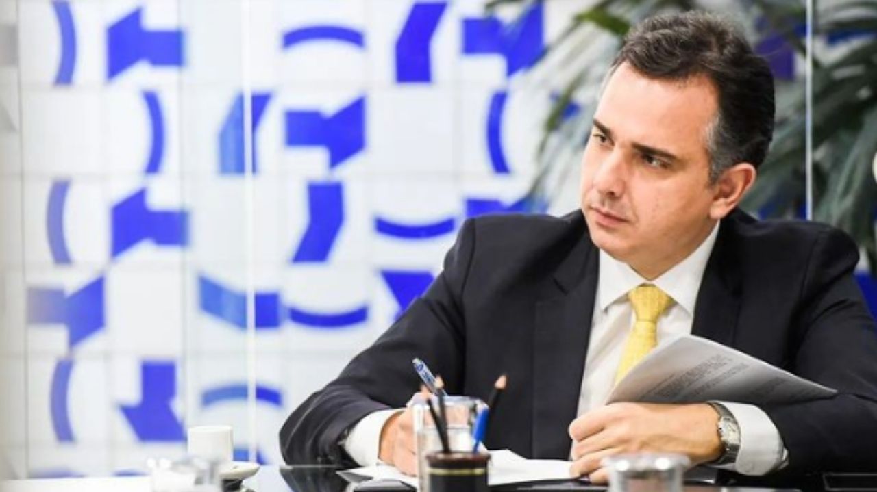 Rodrigo Pacheco assinando documento e olhando para o lado