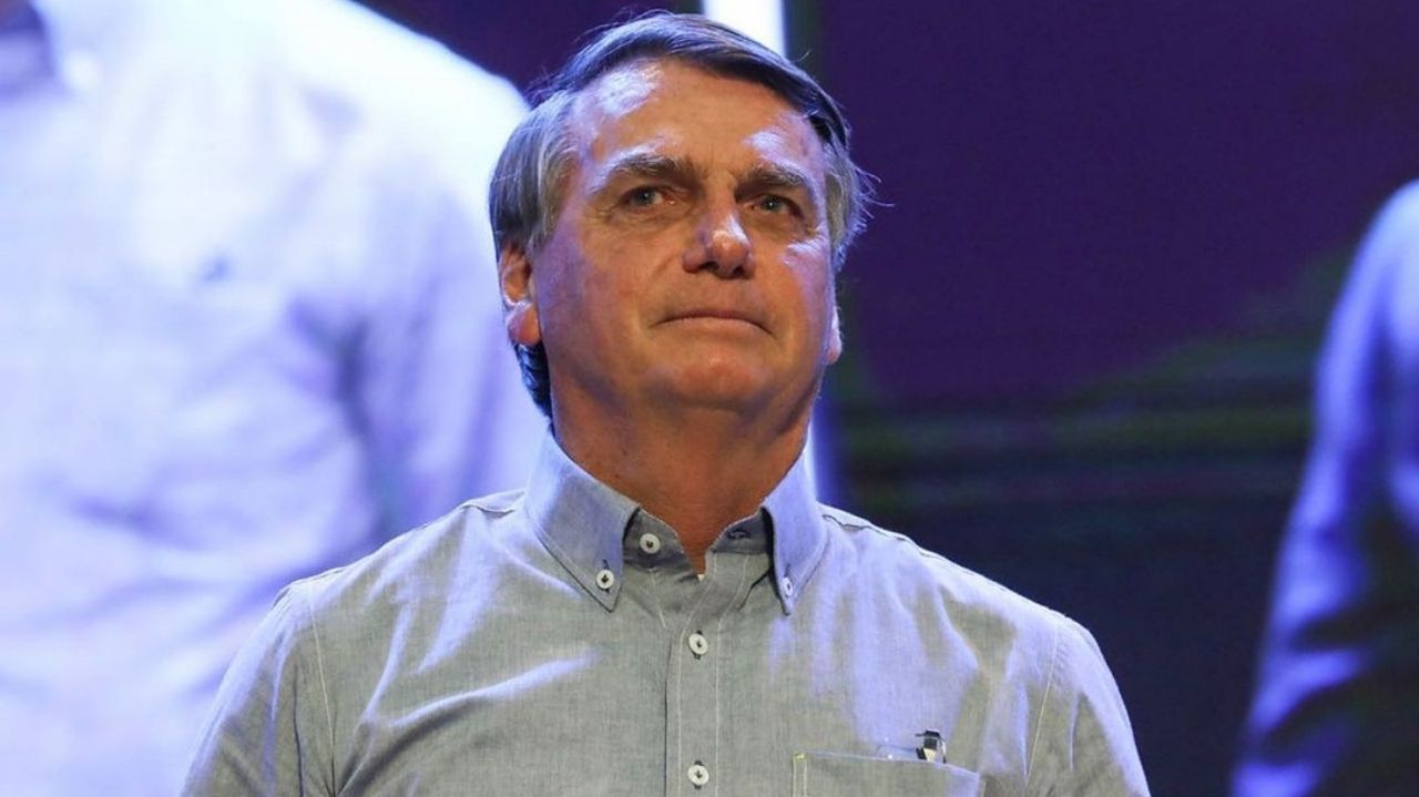 Jair Bolsonaro com expressão séria, vestindo camisa social azul