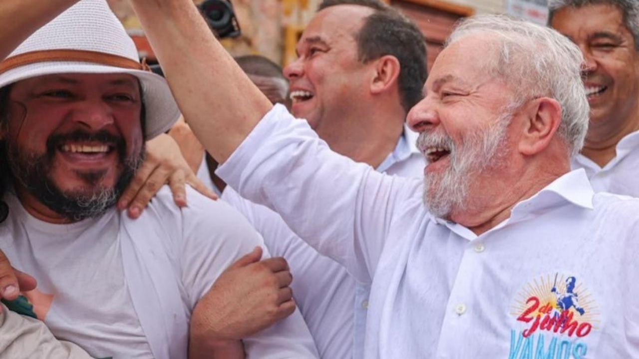 Lula de camisa social branca sorrindo e apertando a mão de populares