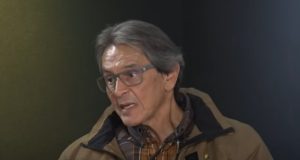 Roberto Jefferson de óculos e casaco marrom, falando e olhando para seu lado direito