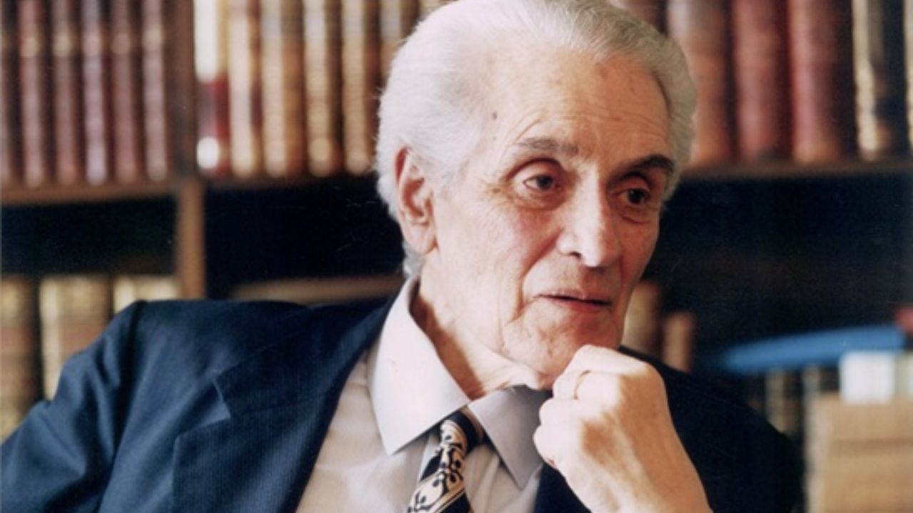 Goffredo da Silva Telles Jr. de terno e gravata, com expressão séria e mão no queixo