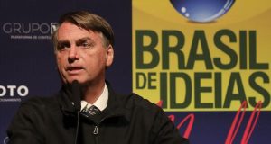 Jair Bolsonaro com expressão séria e olhando para o lado, vestindo casaco preto