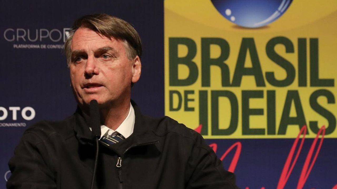 Jair Bolsonaro com expressão séria e olhando para o lado, vestindo casaco preto