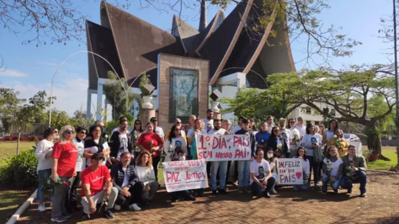 Família e amigos de Marcelo Arruda em ato pela paz, segunrando cartazes perto de igreja e posando para foto