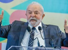 Lula em foto de roupa social, falando em microfone e gesticulando com os braços