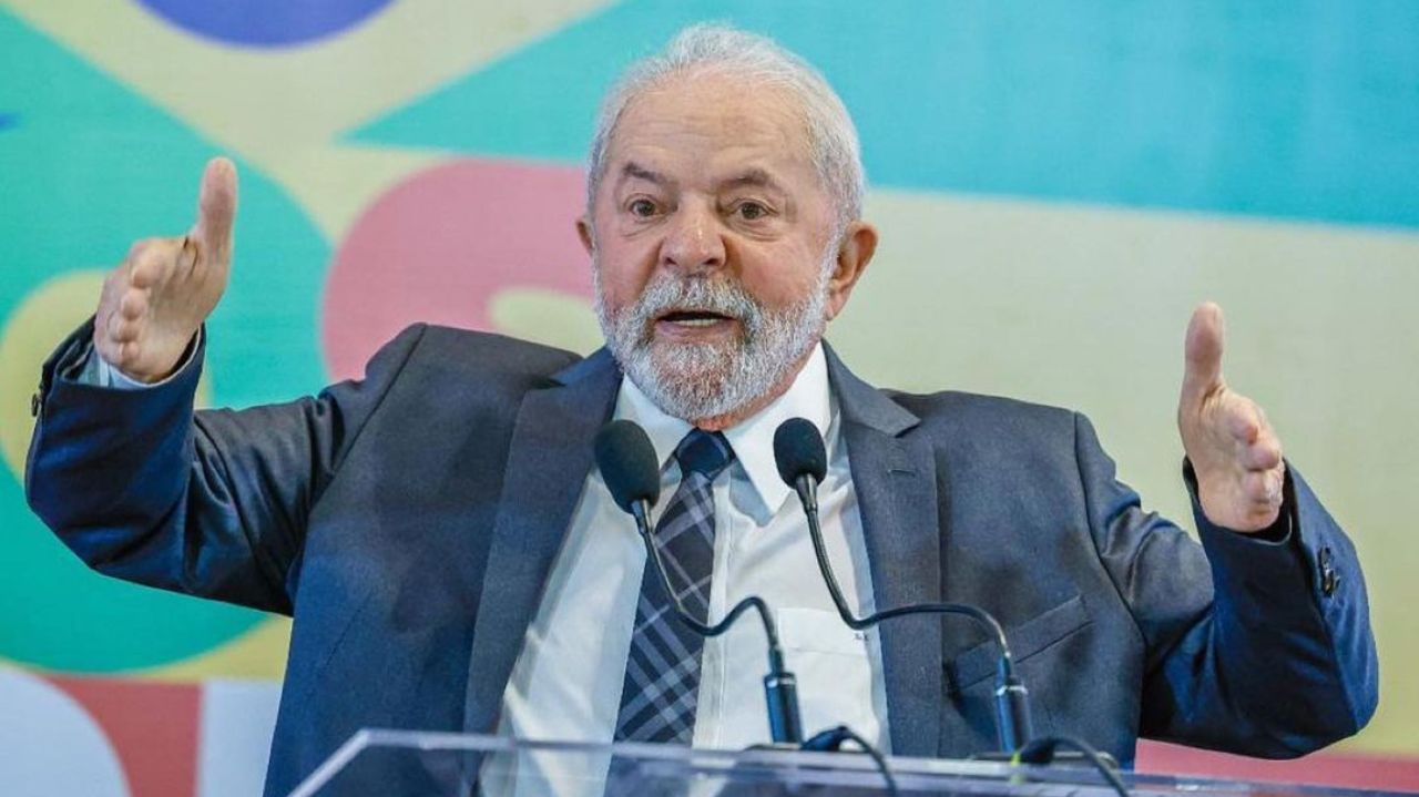 Lula em foto de roupa social, falando em microfone e gesticulando com os braços
