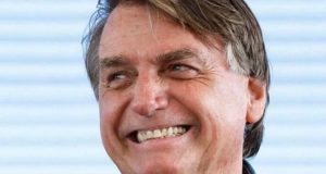 Jair Bolsonaro sorrindo e olhando para o lado em close