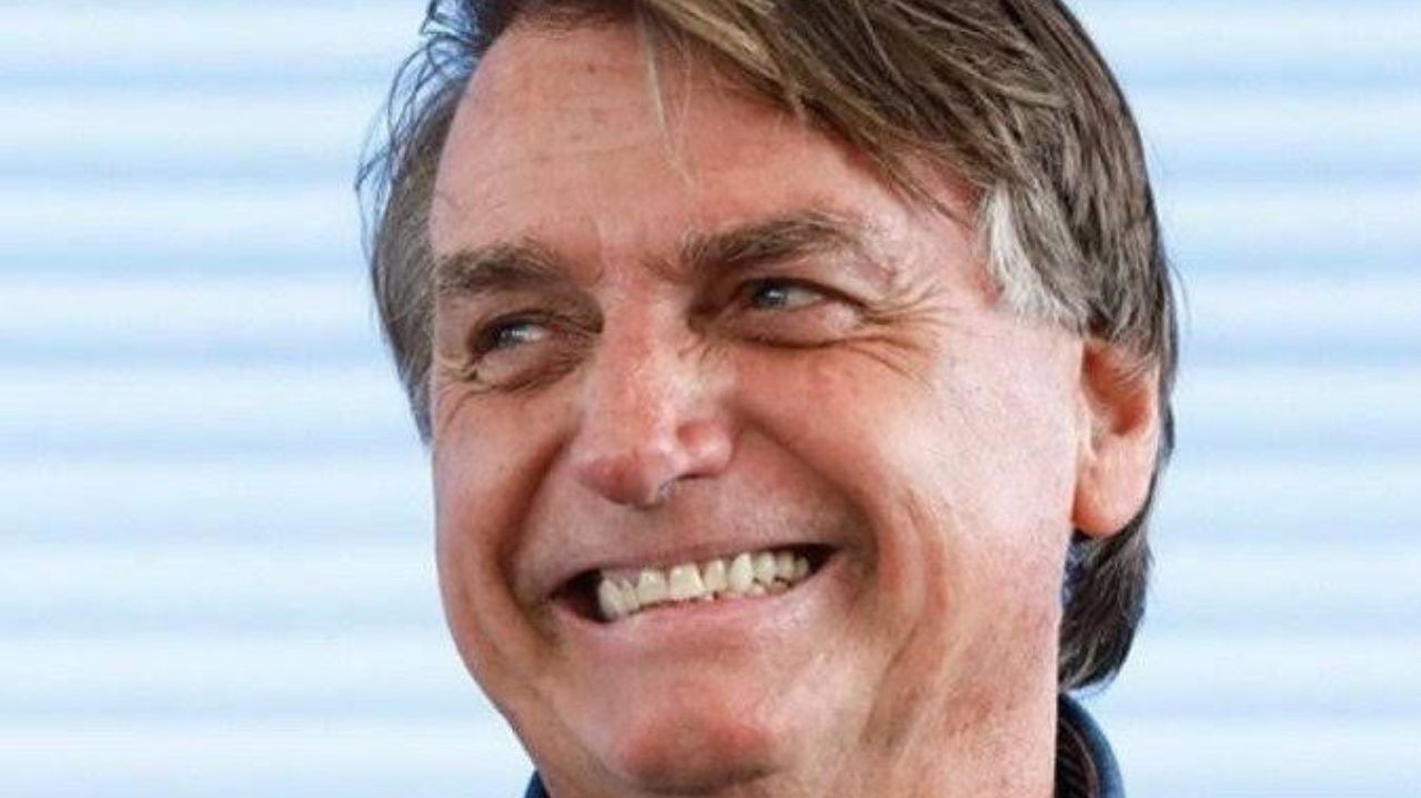 Jair Bolsonaro sorrindo e olhando para o lado em close