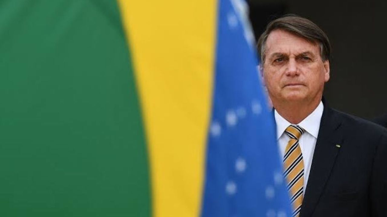 Jair Bolsonaro com bandeira do Brasil em segundo plano