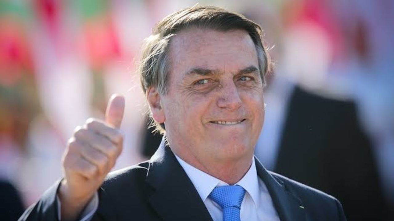 Jair Bolsonaro de terno e gravata fazendo sinal de ok e cara de aprovação