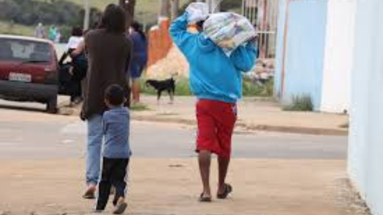 Família caminhando de costas e carregando cesta básica