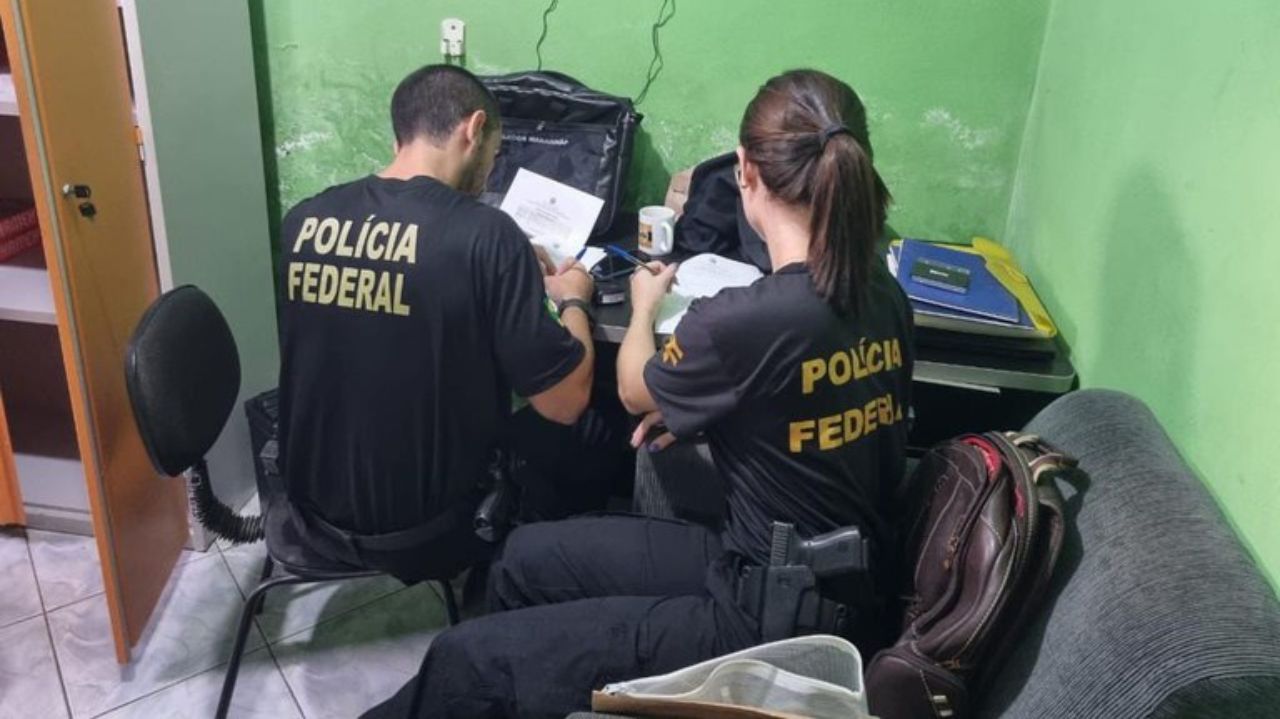 Representantes da Polícia Federal sentados, de costas